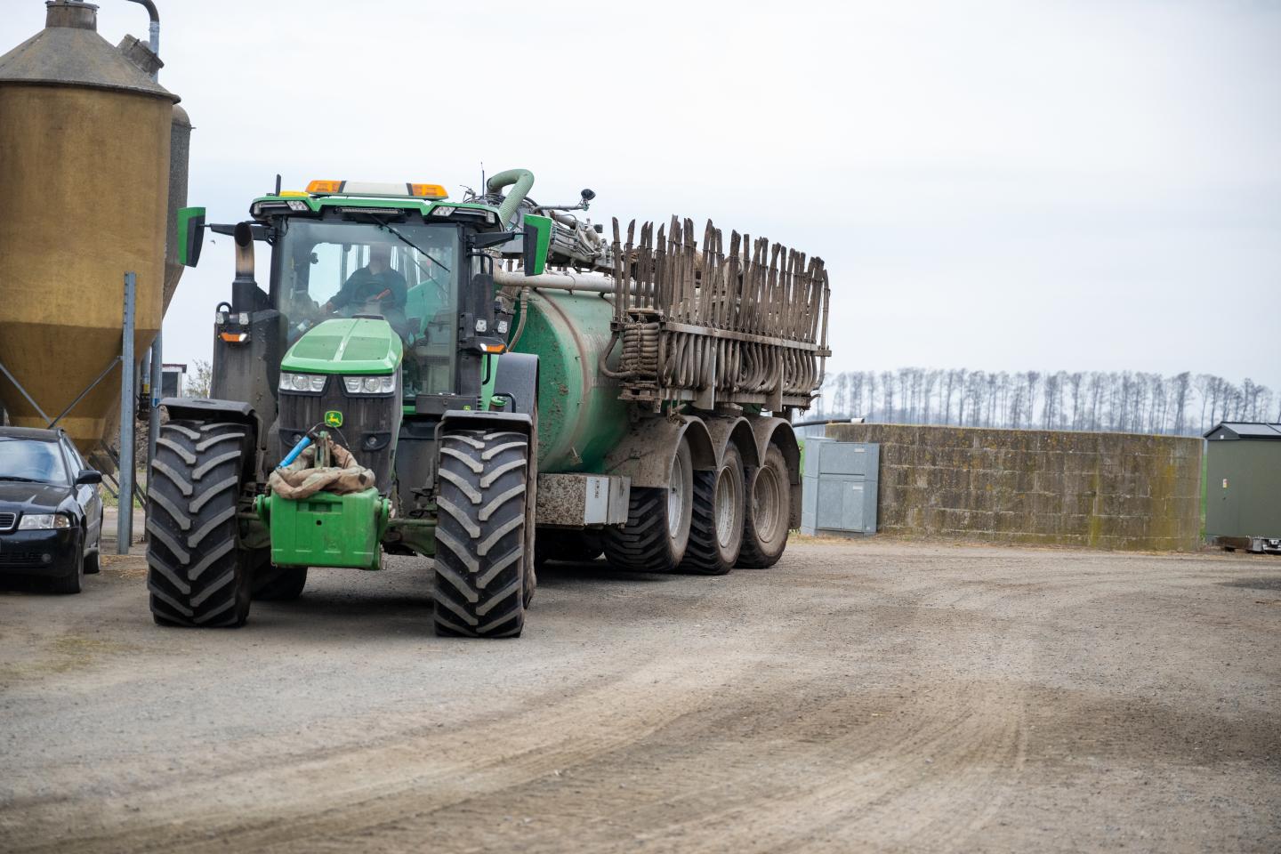 Traktor med släpslangspridare kör mot fotografen