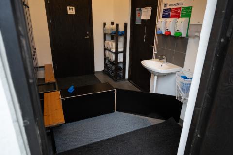 Hygiengräns/hygiensluss i ett fjäderfästall med upphöjd träskiva som markerar ren och oren zon.